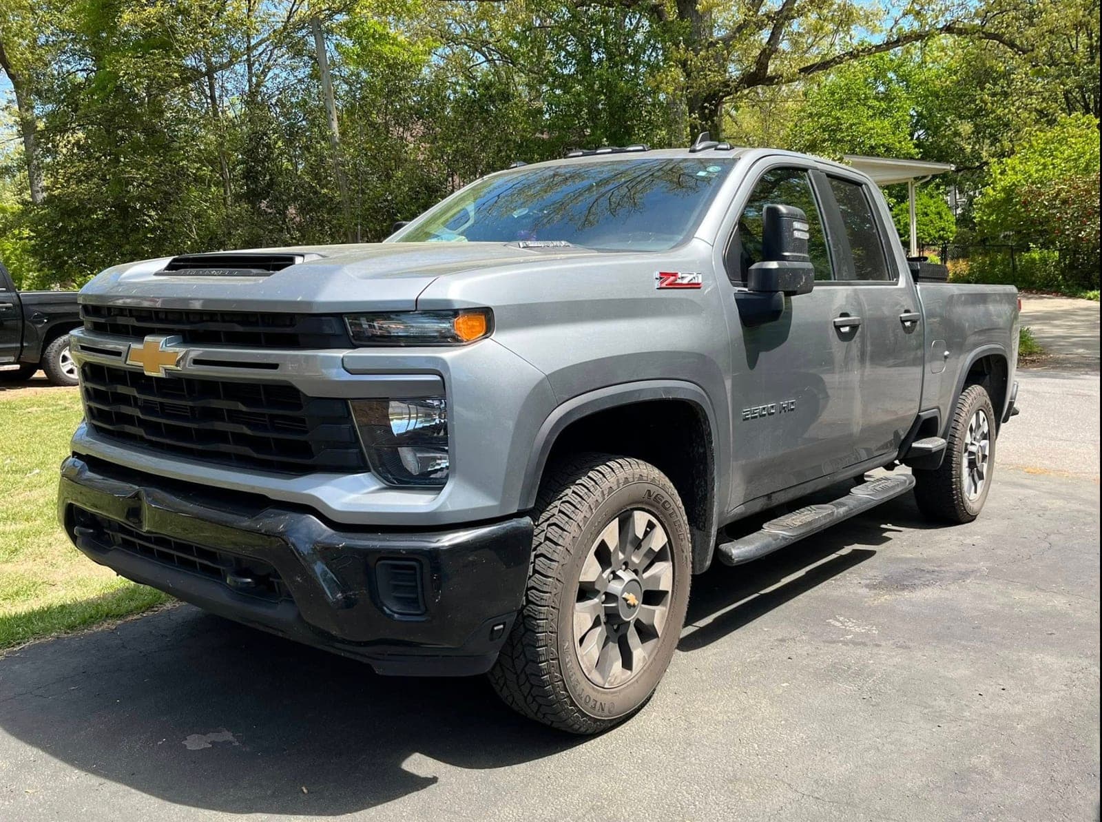 Detailed gray Chevrolet Silverado HD Z71 in a tree-shaded driveway after a full detail by ShineCraft in Olathe.