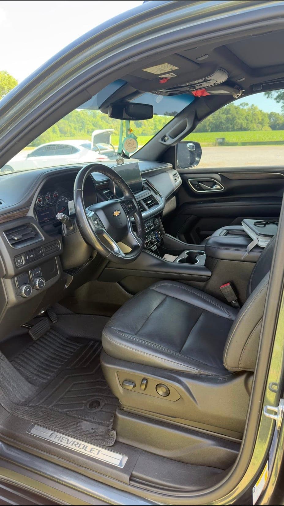 Driver-side leather interior of a Chevrolet Tahoe with the door open, dash and steering wheel cleaned by ShineCraft in Olathe.